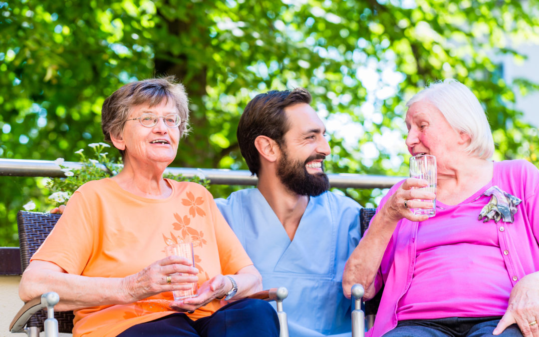 Nurse drinking coffee with seniors on terrace of retirement home