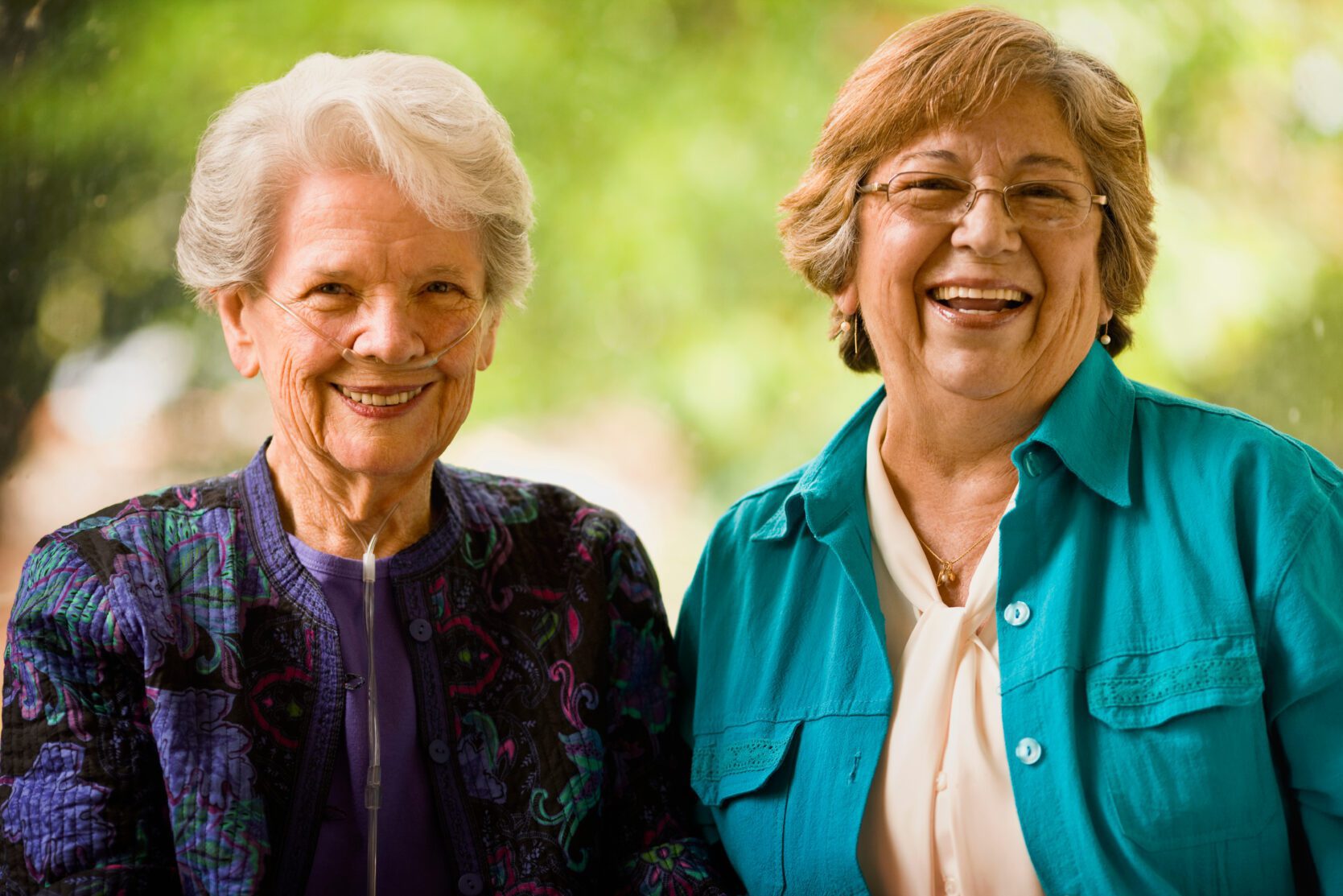 Senior woman with an oxygen nose hose (cannula) and a mature women smile as they pose for a portrait together.