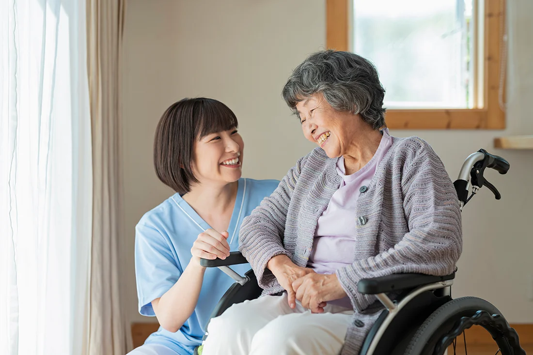 Senior woman in wheelchair indoors with Female Health Care Provider